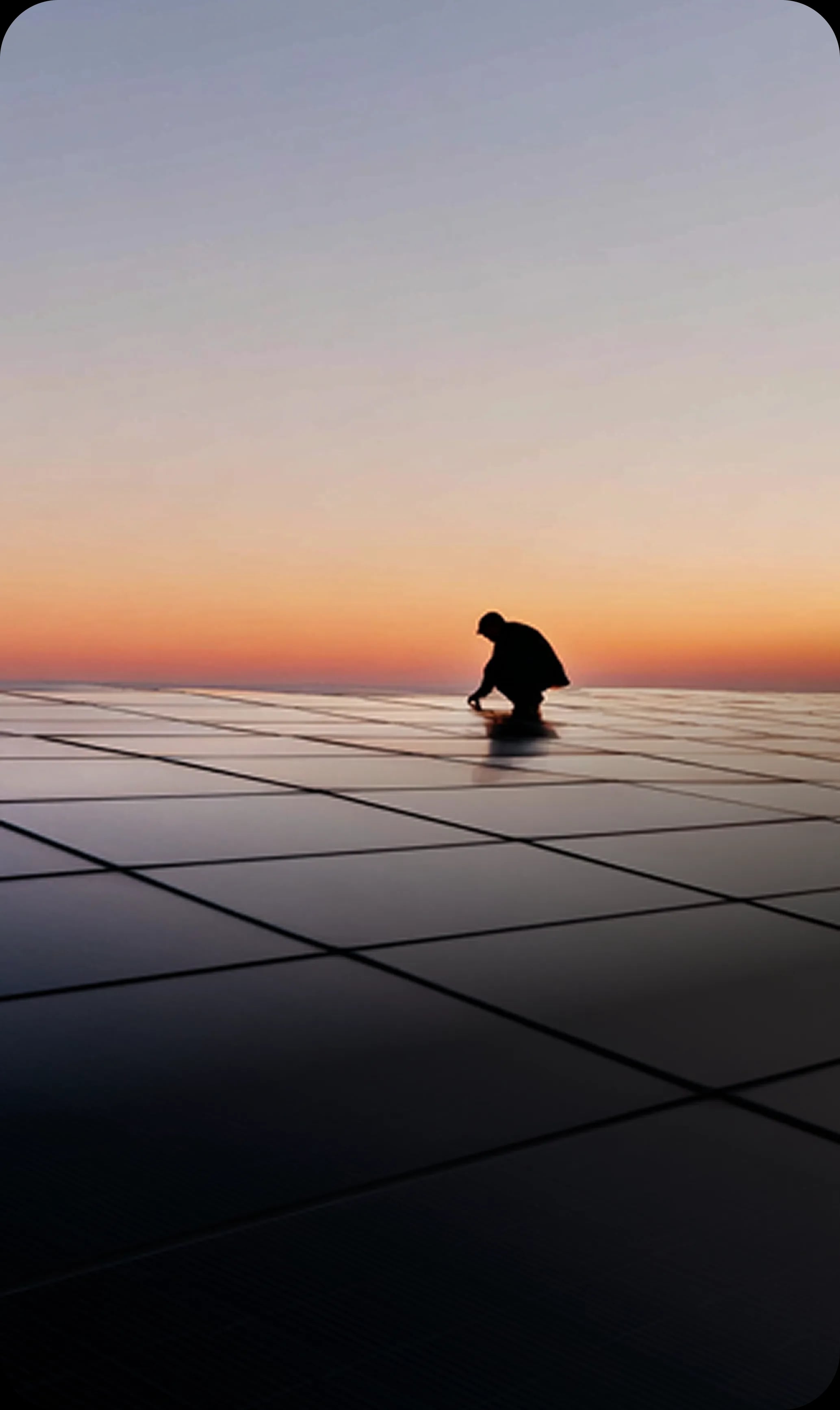 Worker silhouette on solar panels at sunset